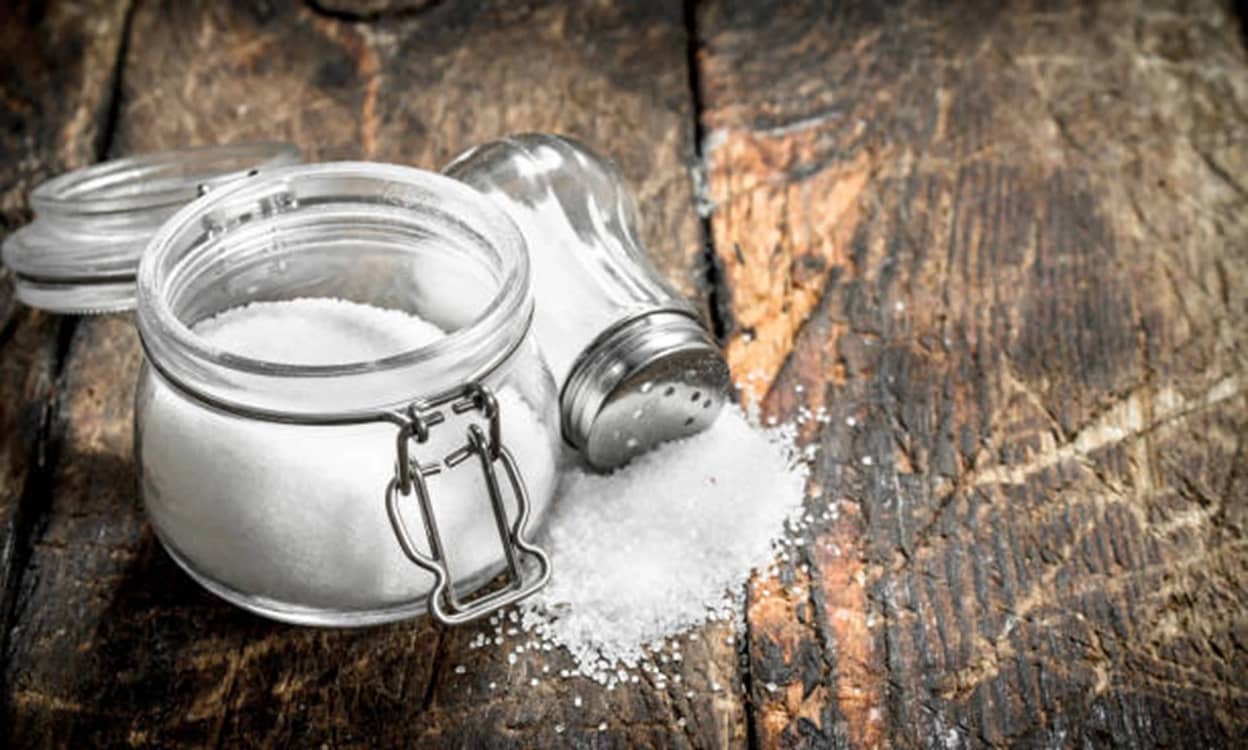 Un borcan cu sare și o solniță cu sare împrăștiată pe masă Foto iStock