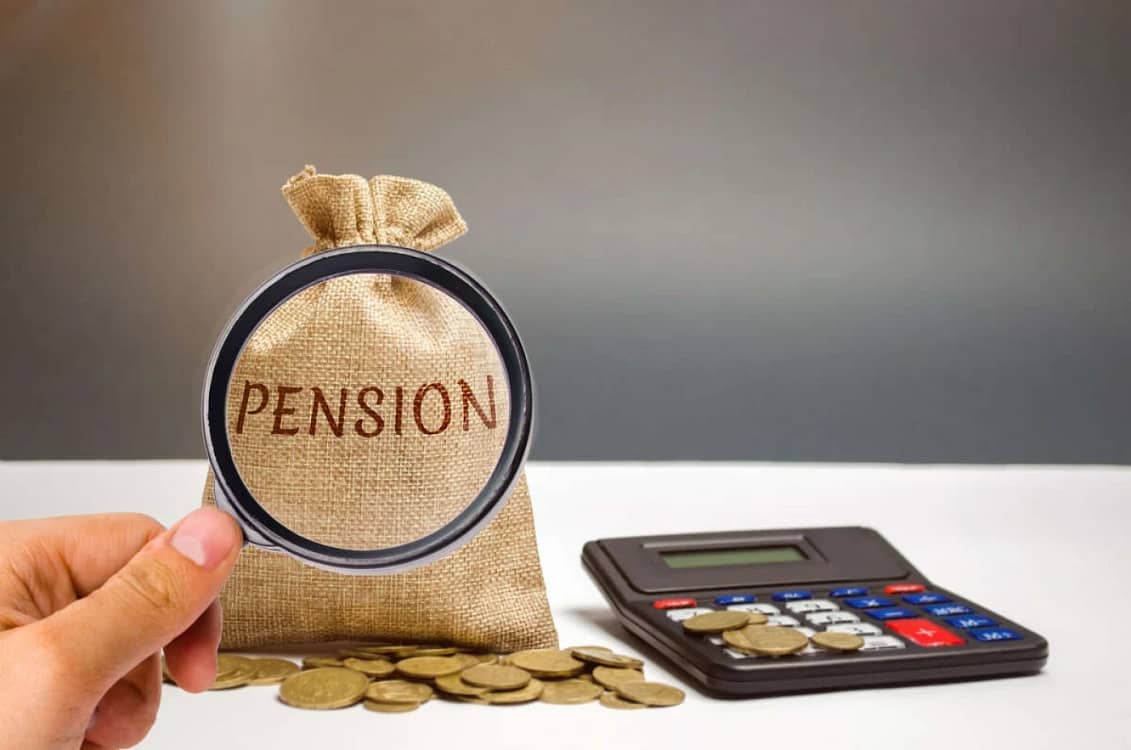 Lupa pusă pe un săculeţ pe care scrie Pension lângă un calculator şi câteva monede