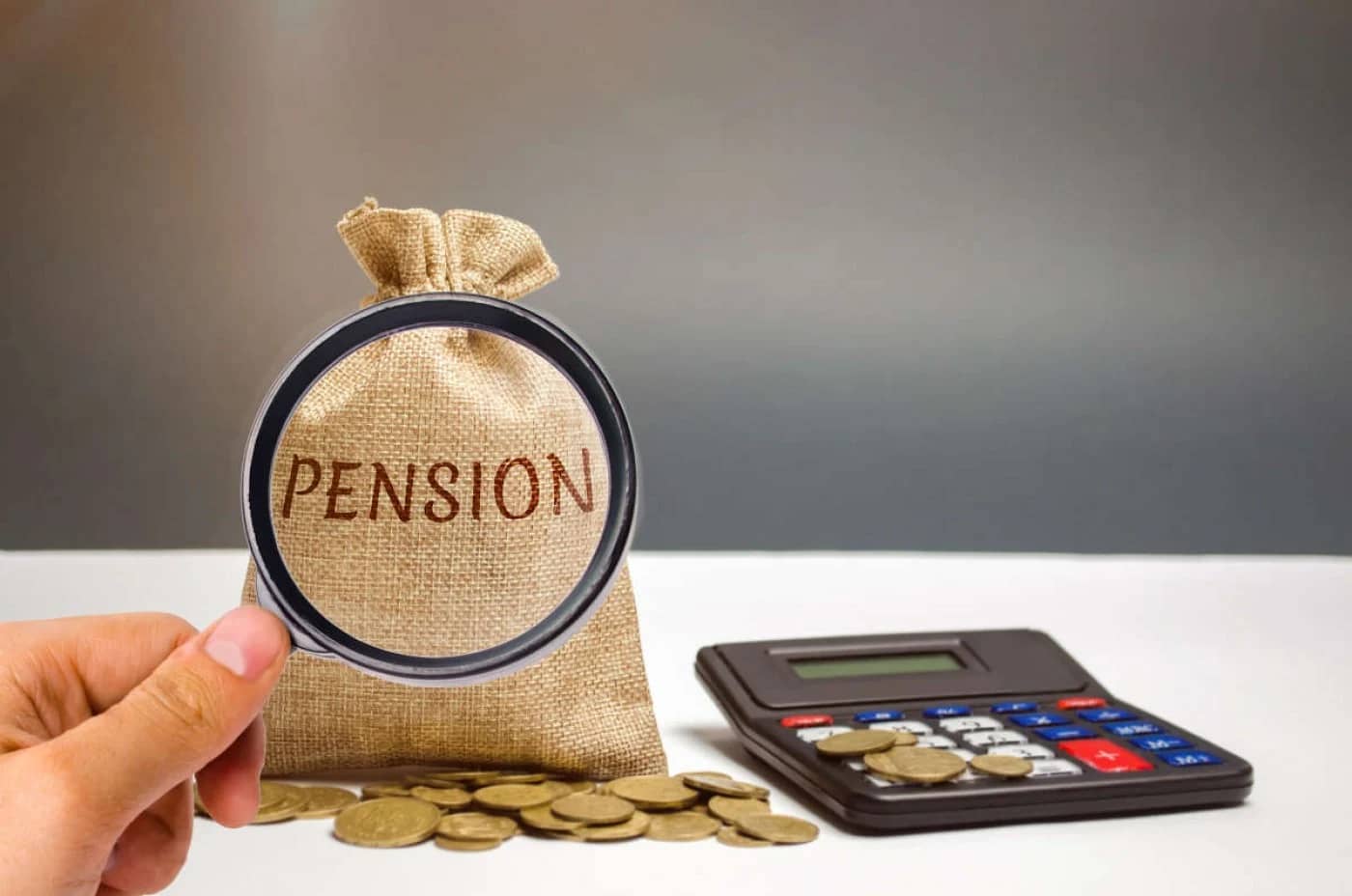 Lupa pusă pe un  săculeţ pe care scrie Pension lângă un calculator şi câteva monede